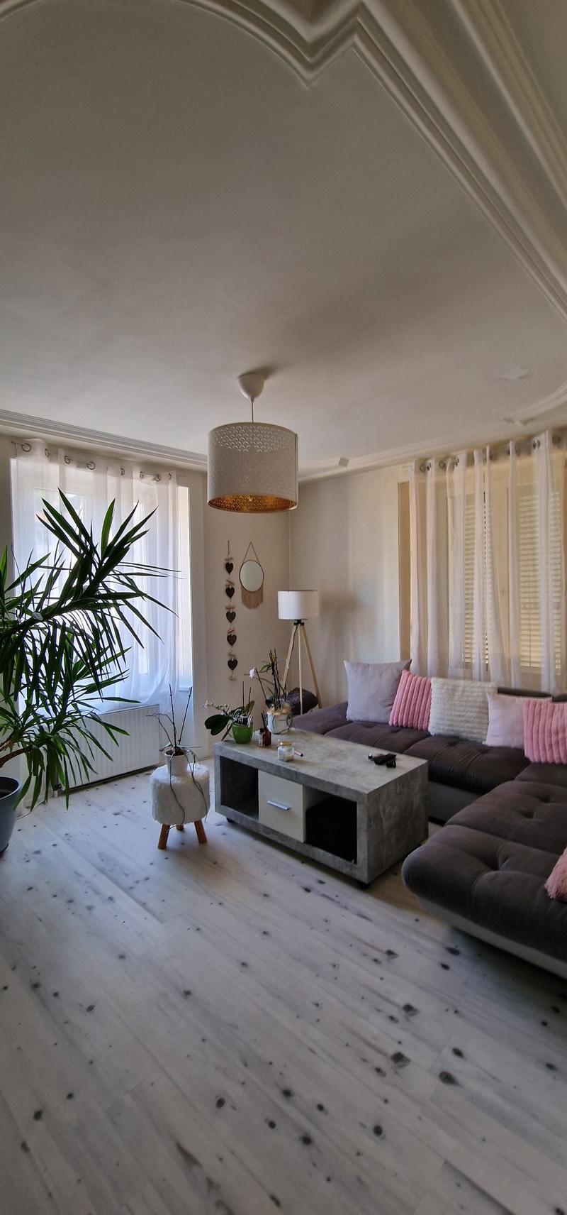 white wooden floor, white walls, large windows, white curtains, large sofa, coffee table, plants, lamp
