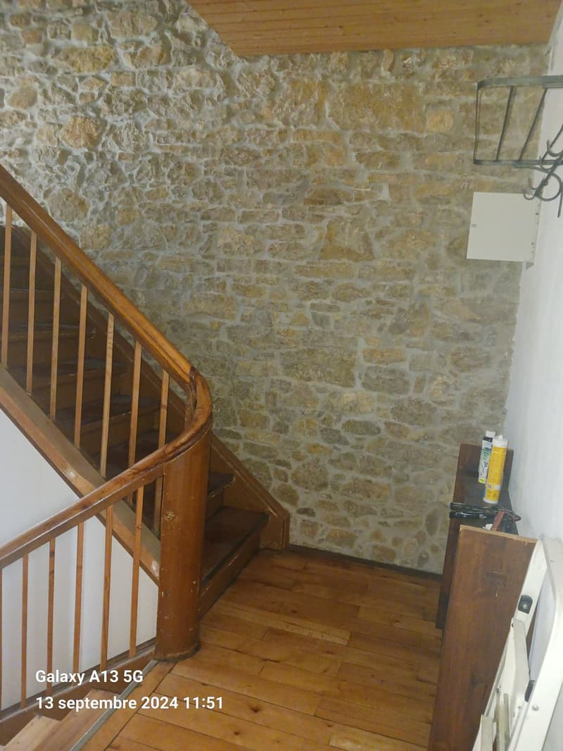 wooden staircase, stone wall, wooden floor, metal rack, wooden table, spray cans