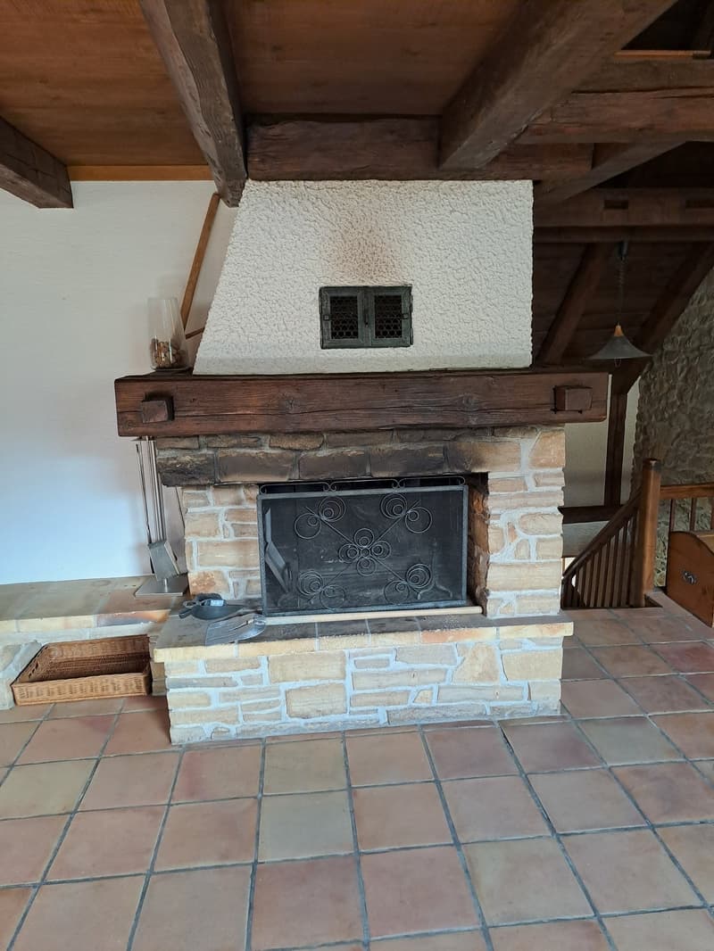 Fireplace with stone wall, wooden ceiling, tiled floor, basket, and a staircase