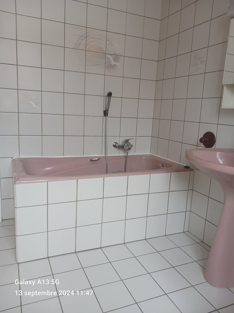 Bathroom with white tiles, pink bathtub, pink sink, silver faucet, shower head