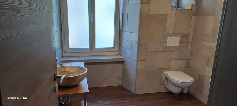 Bathroom with a sink, toilet, and window