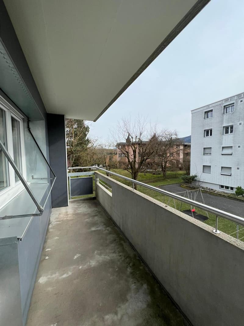 empty balcony with metal railings, concrete floor, metal awning, window
