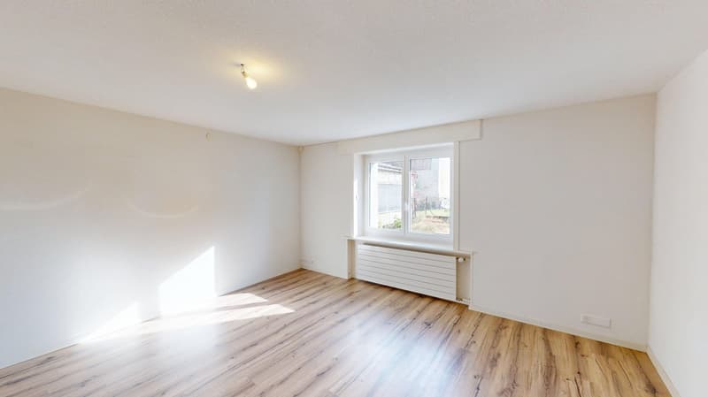 empty room, white walls, wooden floor, white radiator, single light fixture, single window