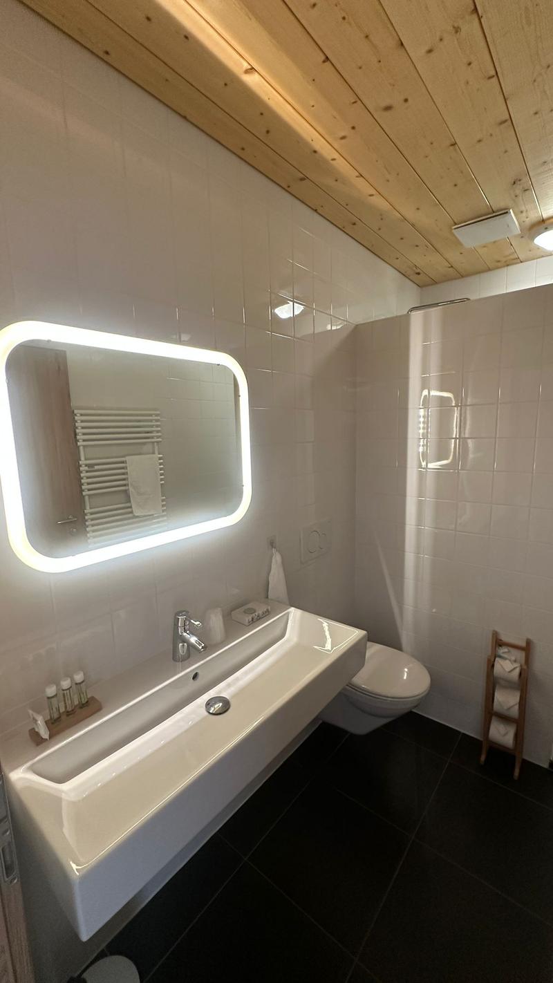 Bathroom with shower, sink, toilet, and wooden ceiling.