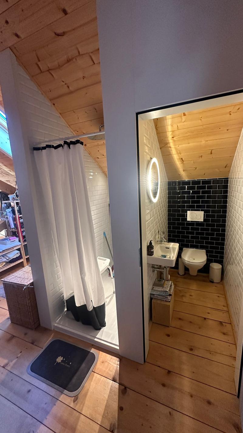 shower area with curtain, toilet, small sink, wooden flooring