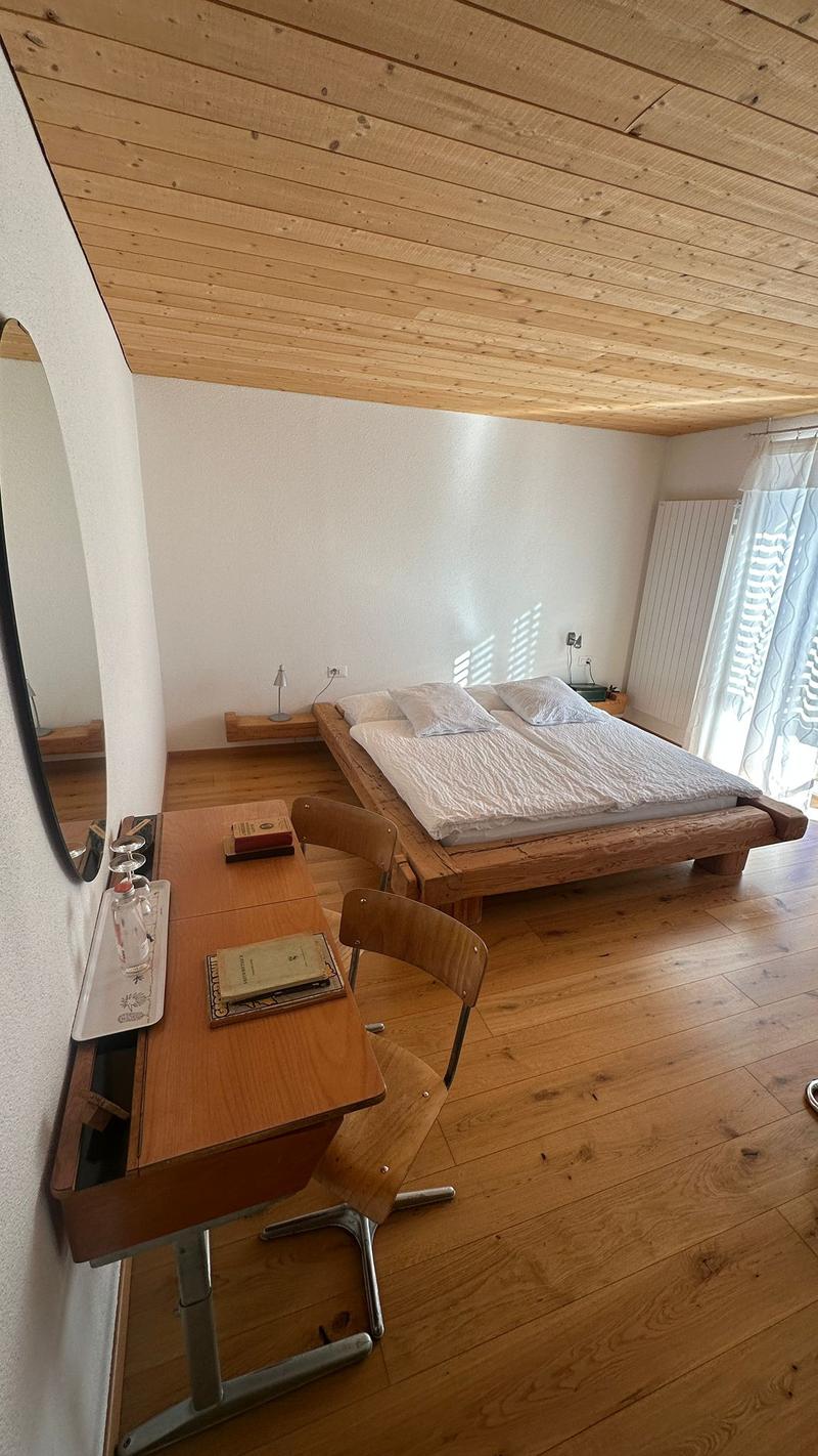 bedroom with bed, desk, chair, mirror, lamp, books, nightstand, lamp, electrical outlet