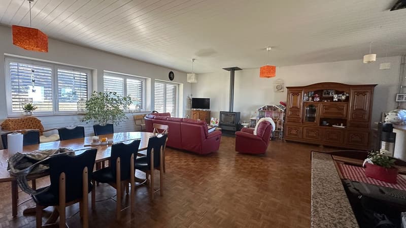 living room, dining room, red couch, large windows, wooden flooring, table, chairs, TV, fireplace