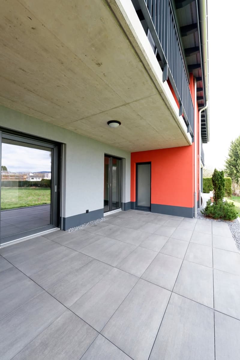 modern building, gray and orange walls, large glass doors, tiled floor, balcony