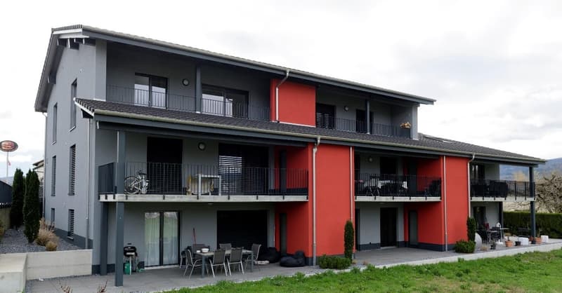 2 story house, gray and red exterior, multiple balconies, outdoor dining area, bicycles