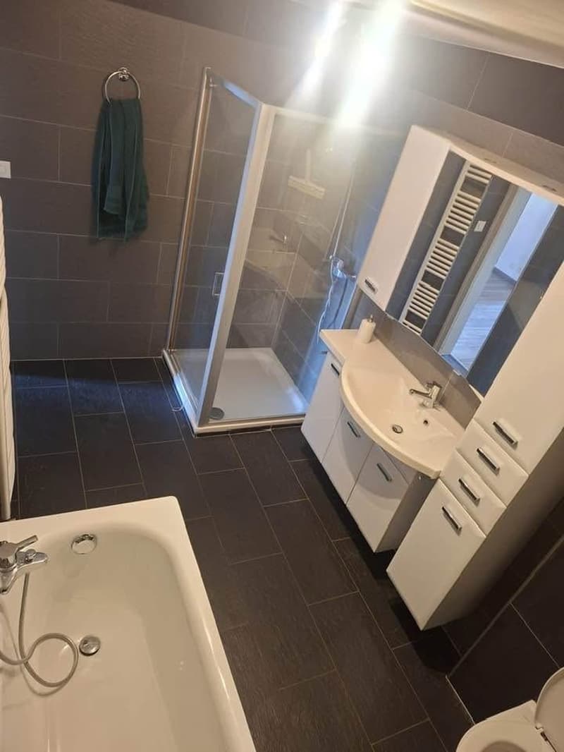 Bathroom with bathtub, shower, sink, toilet, cabinets, and towel rack