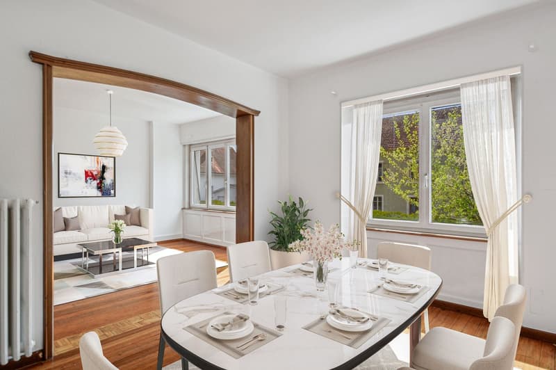 Dining room with a marble table, white chairs, a white couch, a coffee table, a radiator, a picture frame, and a potted plant.
