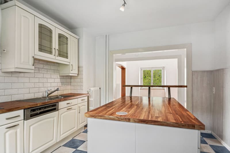modern kitchen with white cabinets, wooden countertops, stainless steel sink, dishwasher, white tiled backsplash, white ceiling, white walls, white and blue checkered floor