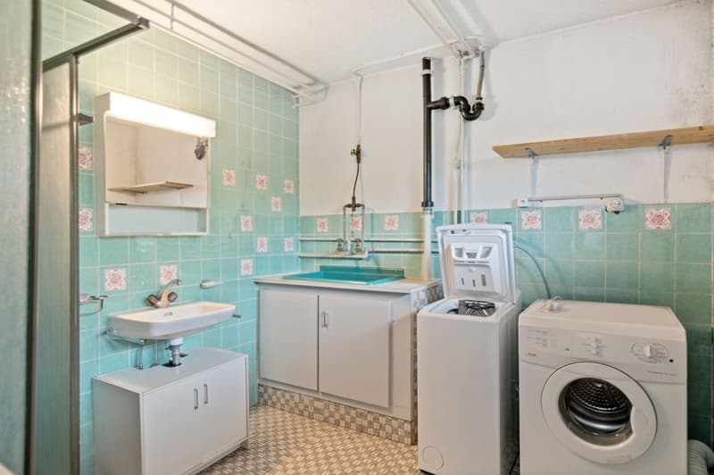 Bathroom with teal tile walls, sink, vanity, washing machine, and dryer