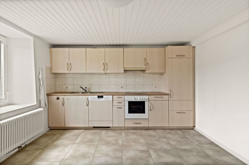 Spacious kitchen with beige cabinets, built-in oven, and tile flooring.