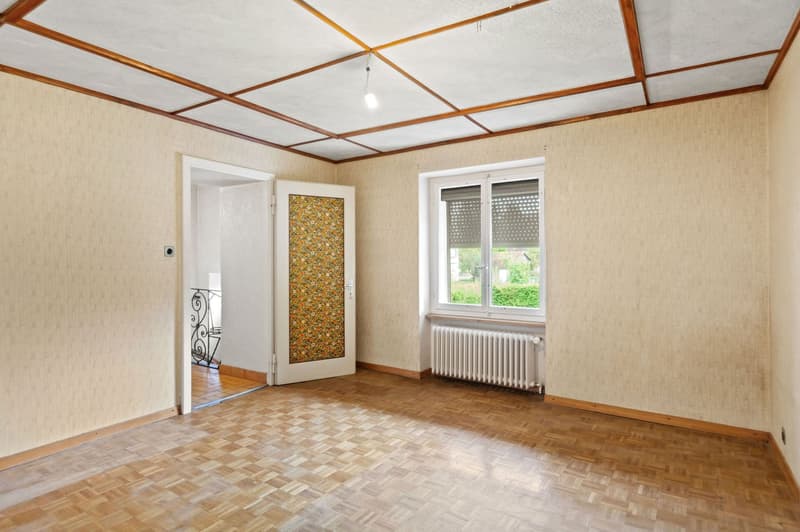 wood floor, white radiator, patterned door, open door, window with shutters