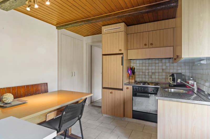 Open kitchen, wooden cabinets, tile flooring, table with chairs, sink, stove, refrigerator, wooden ceiling