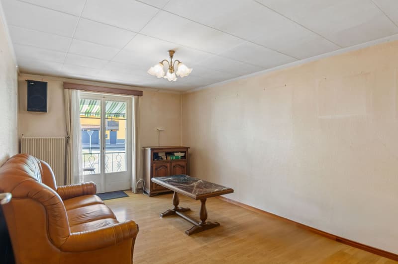 Wooden floor, light beige walls, leather sofa, fireplace, center table, glass door, balcony, cabinet