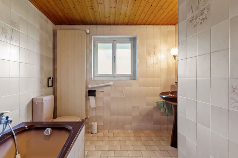 Tiled walls, bathtub, toilet, sink, window, wooden ceiling, wall-mounted lamp, towel hanger, wall-mounted toilet paper holder