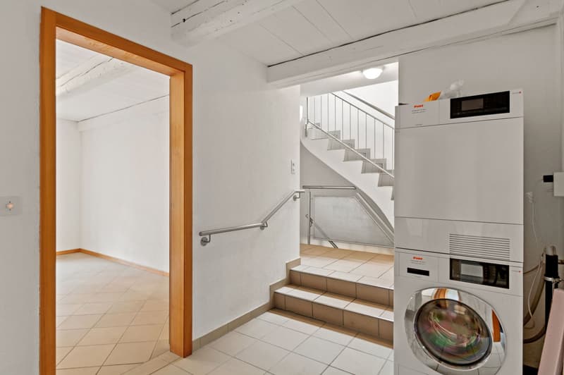 A laundry area with a washer and dryer next to a staircase.