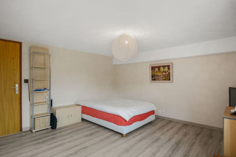 Empty bedroom with bed, shelf, desk, and framed picture on wall