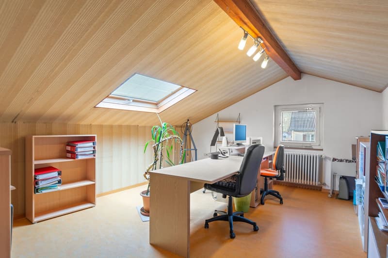 Office with desk, chairs, computer, shelf, potted plant, ceiling lights, small attic window
