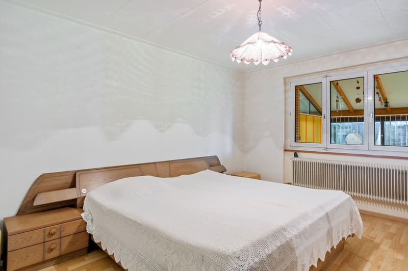 double bed with white sheets, wooden nightstands, large window with curtains, white walls, ceiling lamp