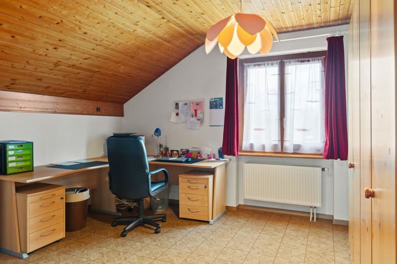 wooden desk, office chair, file cabinets, waste bin, window with red curtains, radiator