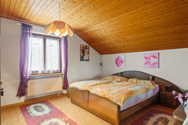 bedroom with a wooden bed, nightstand, window with curtains, radiator, wooden ceiling, carpets, and a decorative lamp