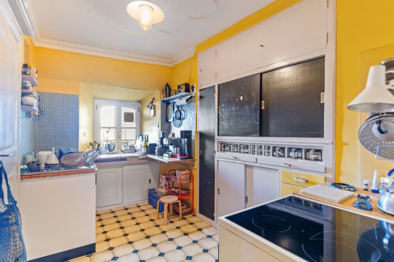 yellow walls, hexagonal tile floor, blue tiles on wall, cabinets, counters, kitchen utensils, stove, fridge, windows