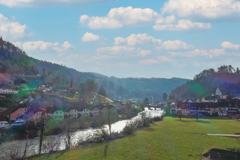 Aerial view of a village with houses, a river, and mountains in the background