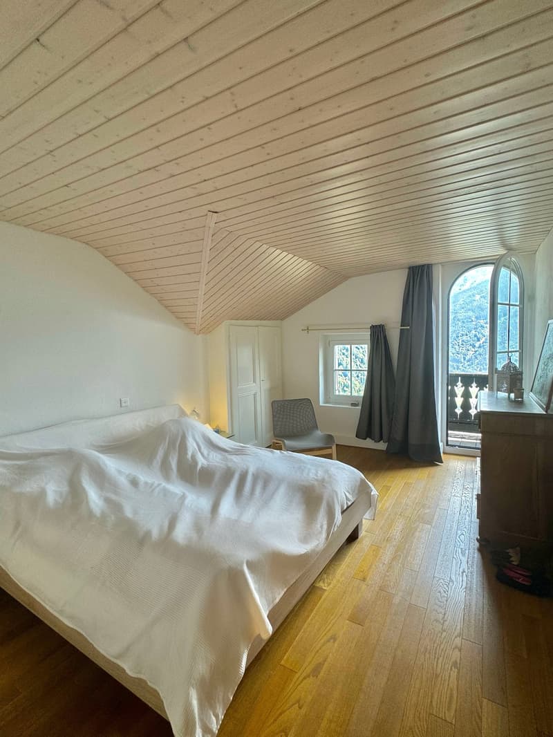 double bed, wooden floor, wooden ceiling, white walls, arched window, balcony with railing