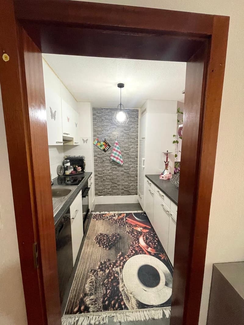kitchen area with countertops, sink, stove, overhead lamp, tiled floor, cupboards, and coffee theme rug