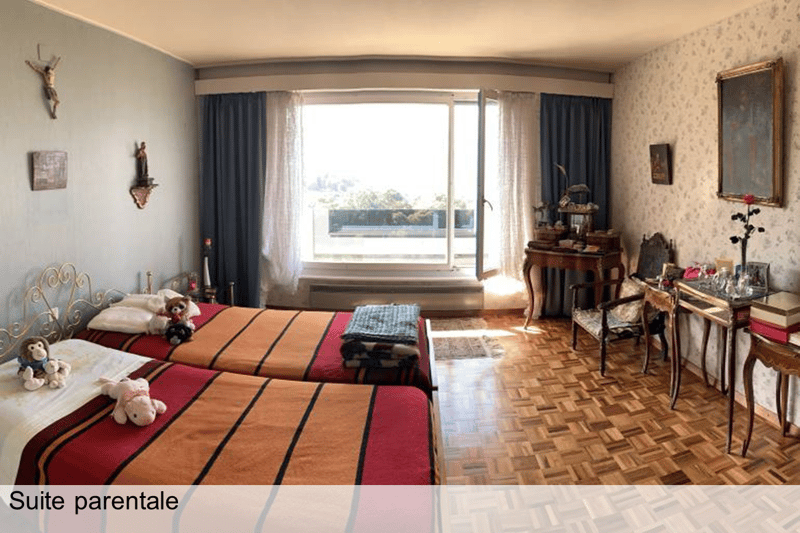 A bedroom with two single beds, a desk with chair, and large window