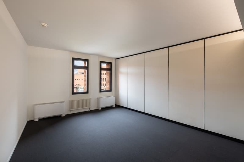 empty room, white walls, black floor, two windows, radiators