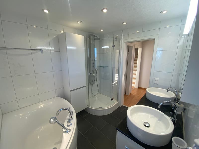 white tiled walls, modern shower stall, bathtub, two sinks, black floor, white fixtures