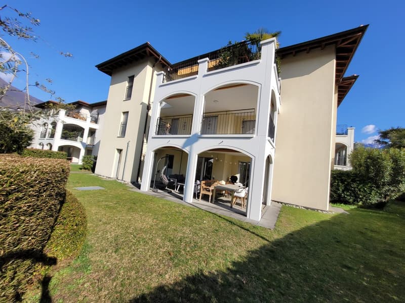 Two-story house, white exterior, multiple balconies, garden, outdoor seating area