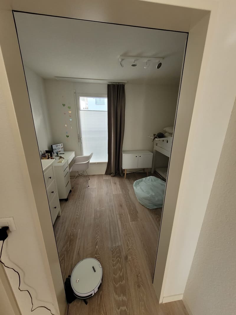 room with wooden floor, white walls, desk, chair, cabinet, bean bag, mirror