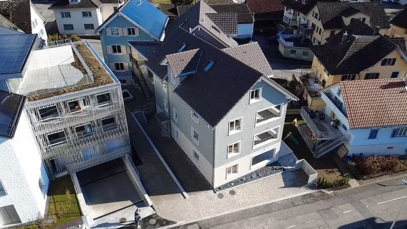 Multi-story building with 4 floors, multiple balconies, solar panels on the roof, raised ground floor
