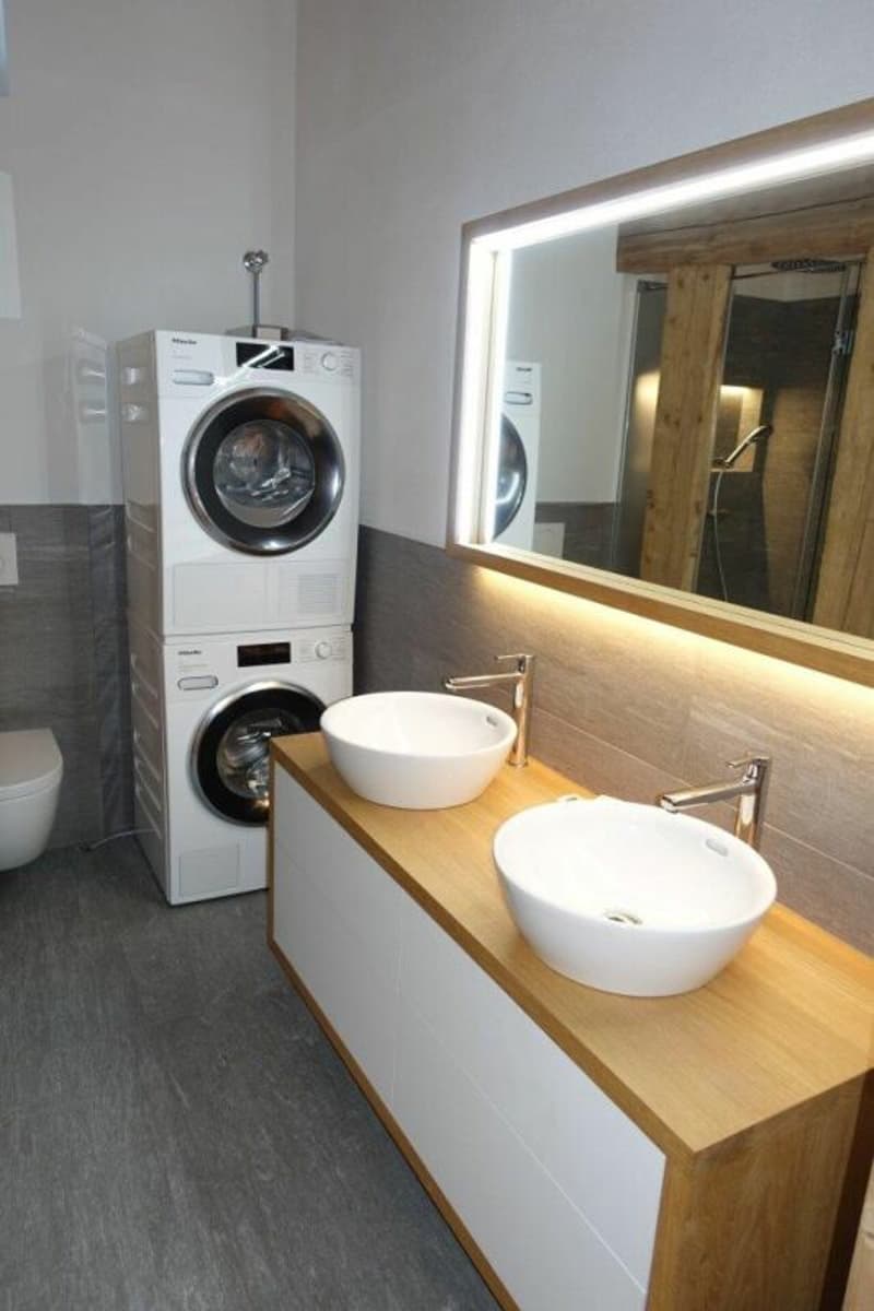 Die Nasszelle mit Doppellavabo, Toilette sowie Waschmaschine und Tumbler