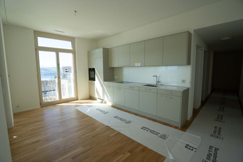 modern kitchen with white cabinets, wooden floor, large window, balcony
