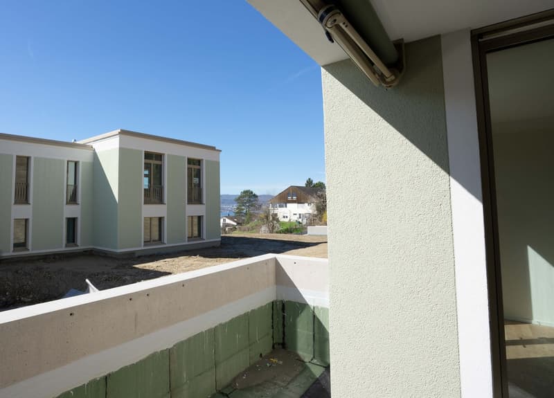 Building with balcony, green and white walls, view of the mountains