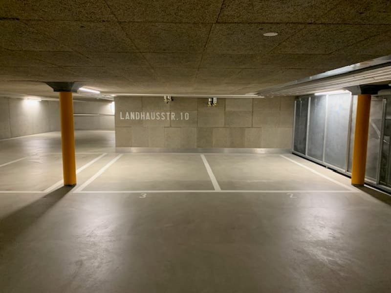 Empty parking lot with concrete floor, yellow poles, and white markings