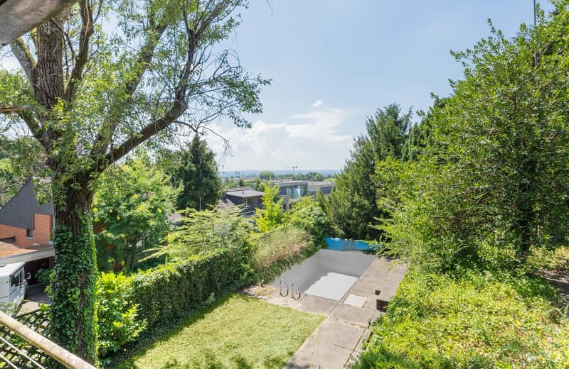 House with garden and swimming pool, fenced bushes, view over the area, blue pool cover, trees