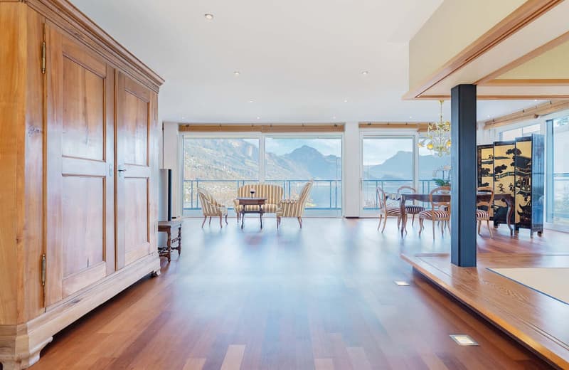 Hardwood floors, large windows, chandelier, large wooden cabinet, round dining table, striped chairs, side table
