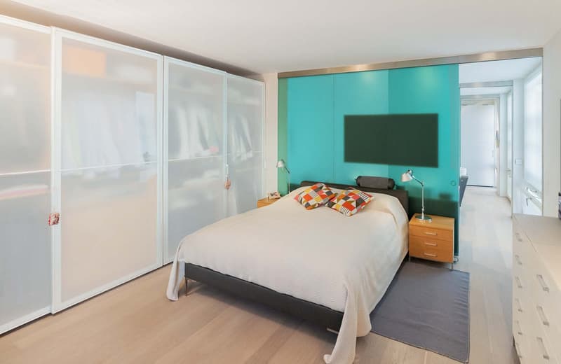 Double bed, bedspread, lamps, wardrobes, blue wall, TV, wooden nightstands, drawers, carpet, wooden floor