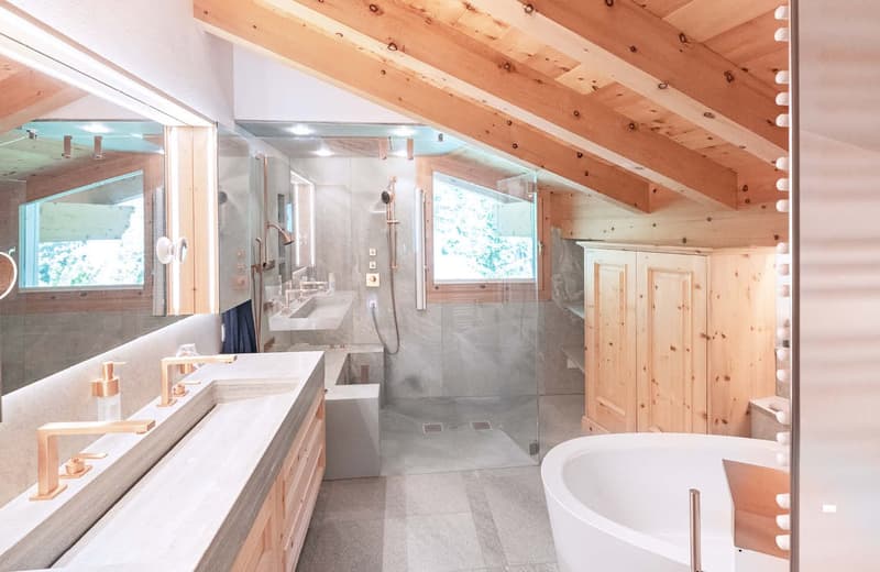 Spacious bathroom with wooden beamed ceiling, large vanity with double sinks, freestanding bathtub, and glass-enclosed shower area