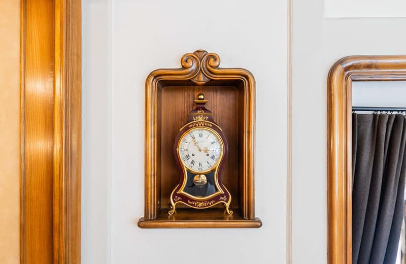 Ornate wooden clock with a gold-colored frame and decorative elements. The clock face displays the time.
