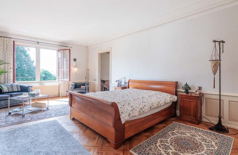 large windows, wooden bed, rug, glass table, couch, lamp