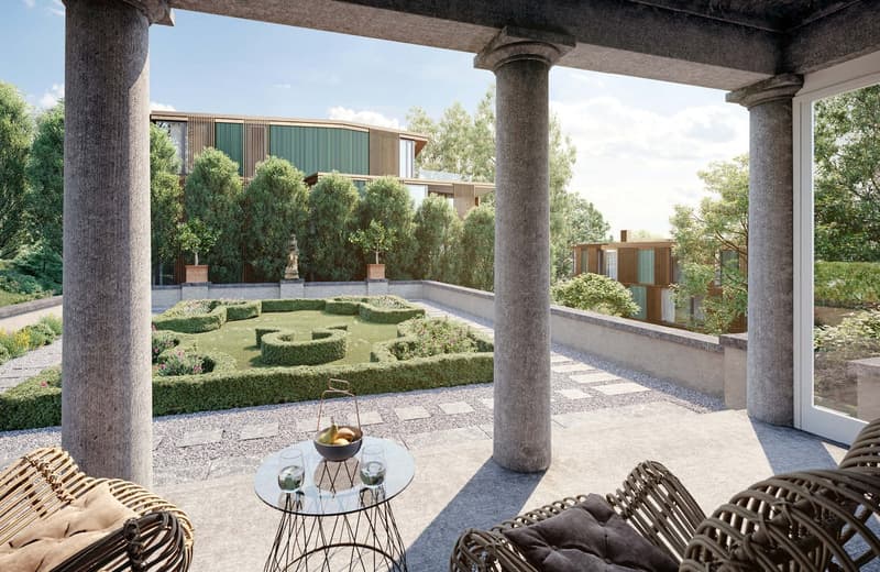 a glass table, chairs, garden with shrubs, statue, pillars, other buildings in the background