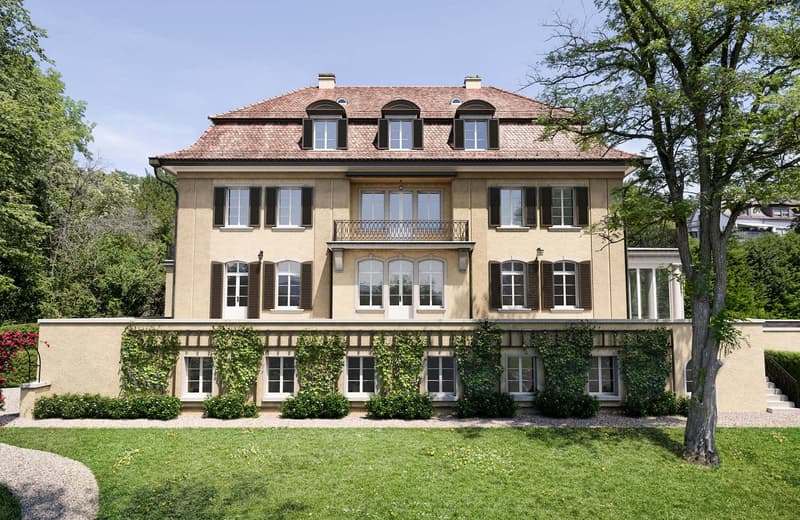 2 story house, beige facade, red tiled roof, multiple windows, balcony, garden